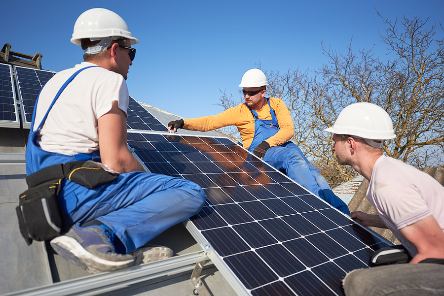 workers holding the solar panel in the roof